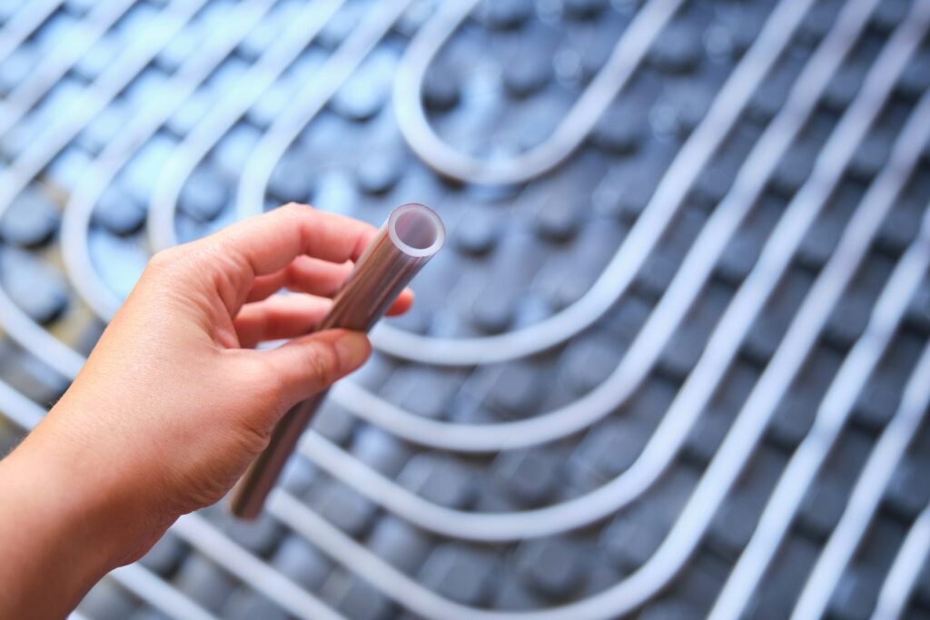 Hand holding a polyethylene pipe used for radiant underfloor system.